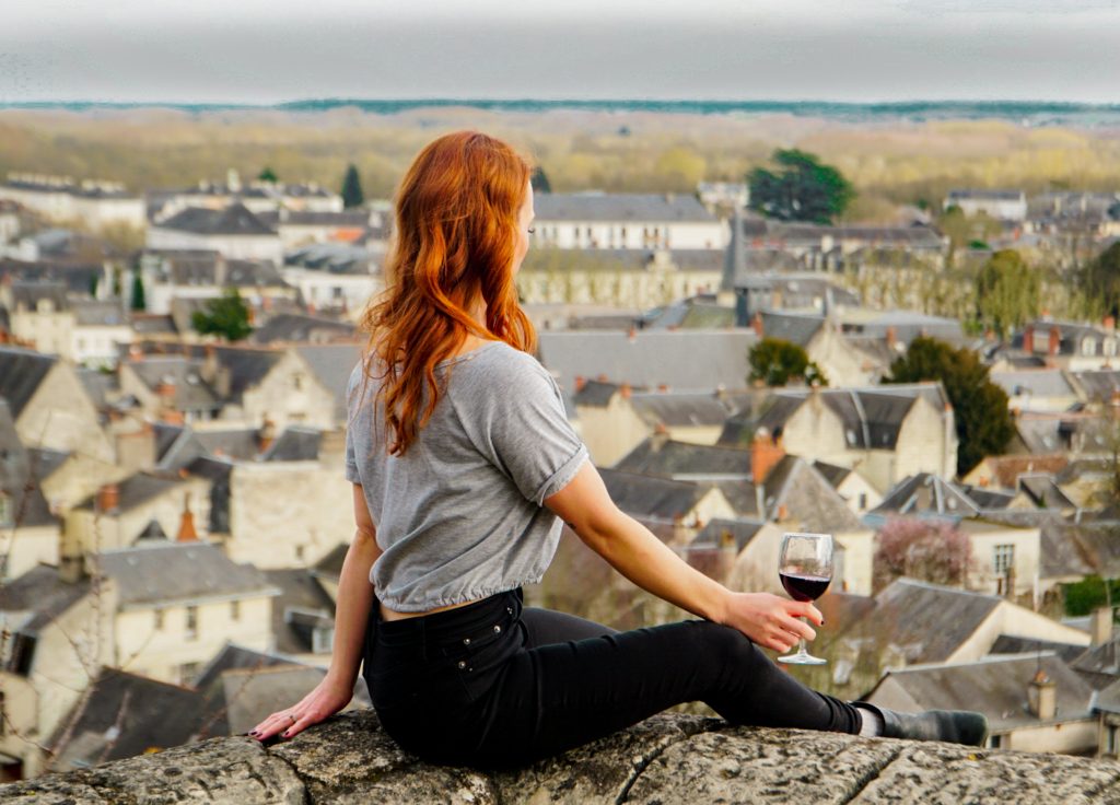 Guide to Loire Valley Wineries, Girl with red hair overlooking chinon with glass of red wine